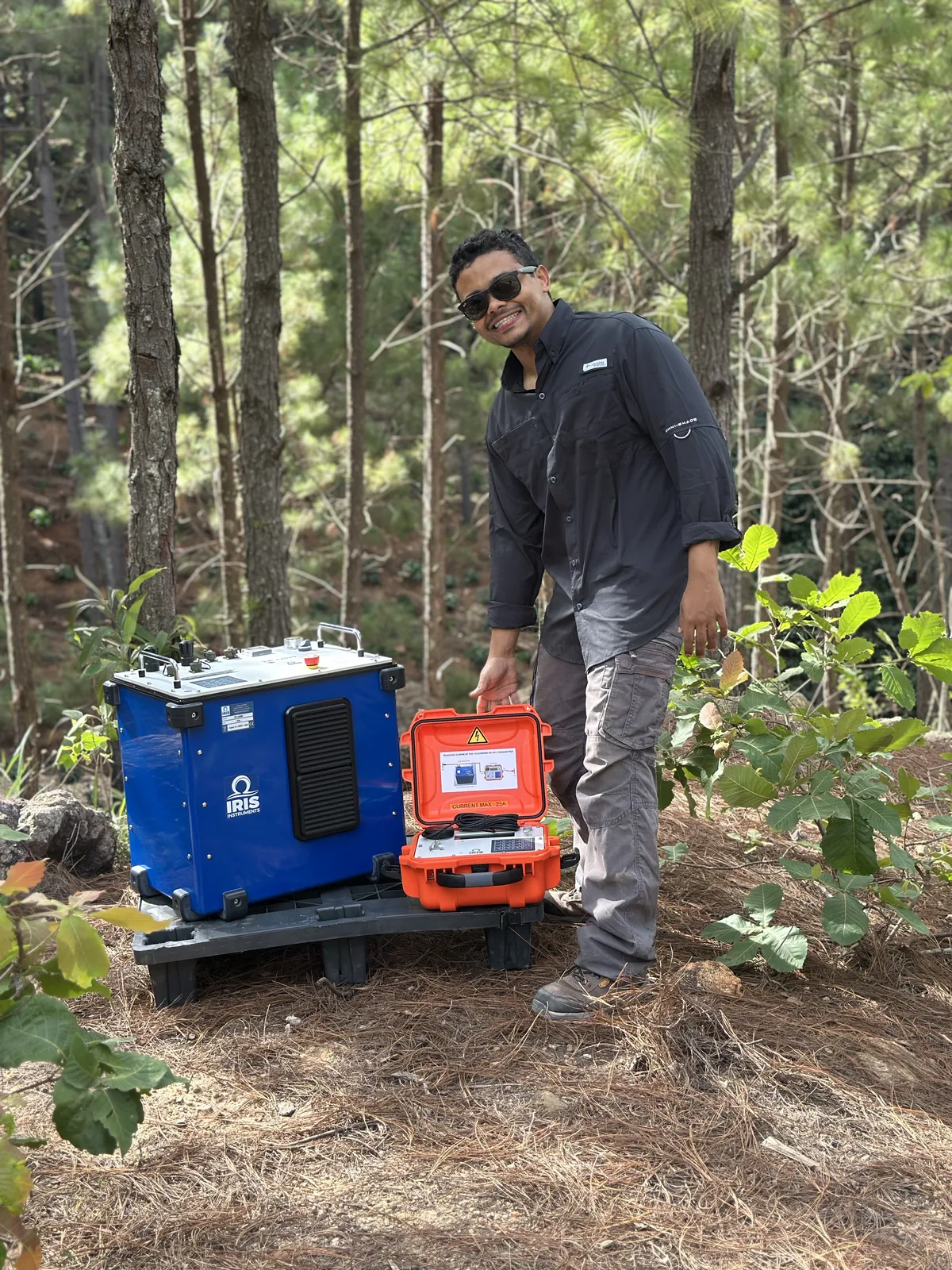 AGG geophysicist with exploration instruments in forest terrain